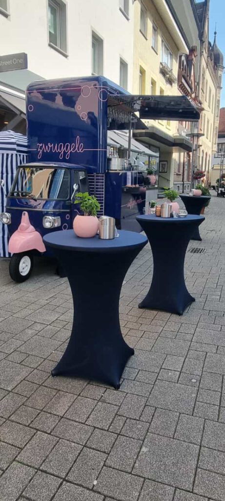 Stehtische mit Blumentöpfen vor dem Zwuggele in der Fußgängerzone