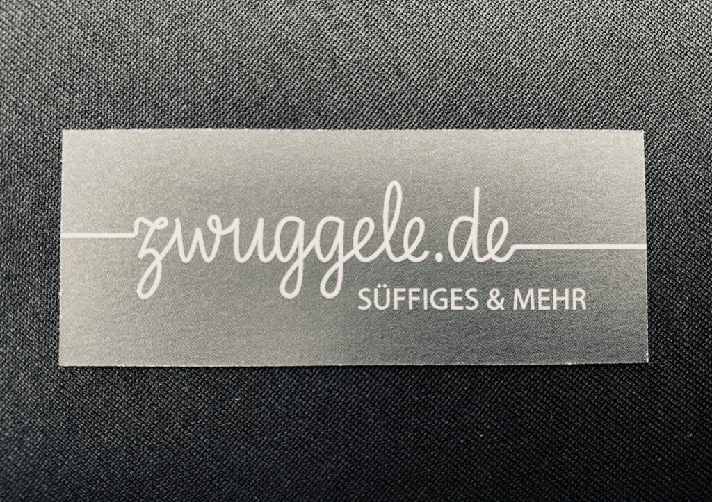 Metallschild mit der Aufschrift zwuggele.de – süffiges & mehr